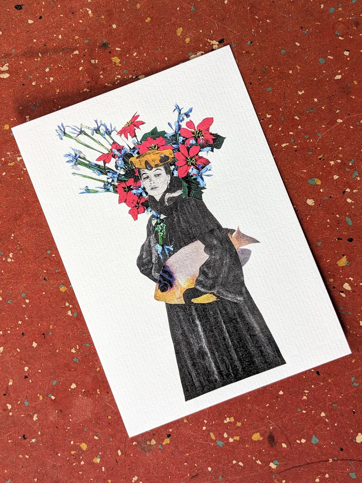 Carte collage reproduction Pistachio.illu Beyond the Sea, femme en robe noire tenant un poisson avec couronne de fleurs colorées sur fond rouge texturé