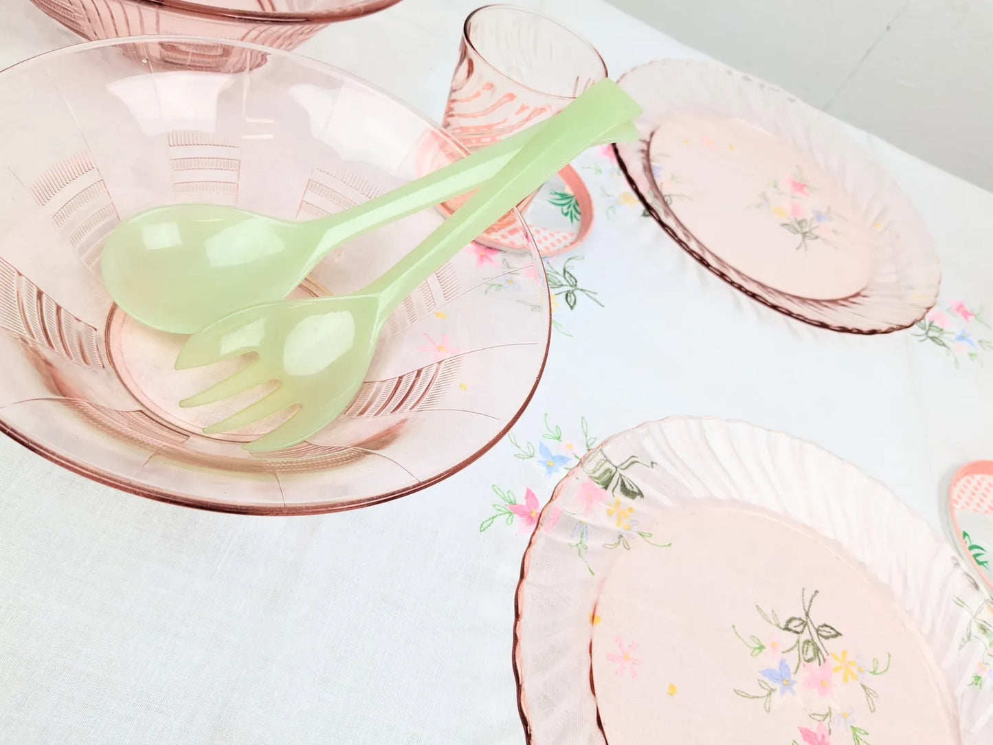 Table vintage avec vaisselle rose en verre et couverts à salade vert pastel en mélamine